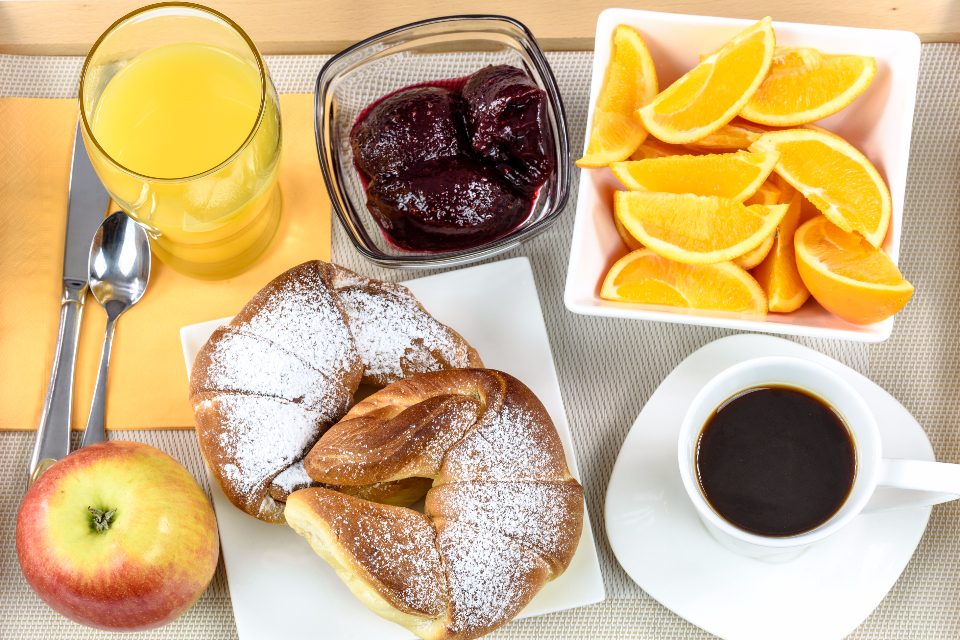 Frühstückstisch mit Kaffee, Gebäck, Orangensaft und Obst